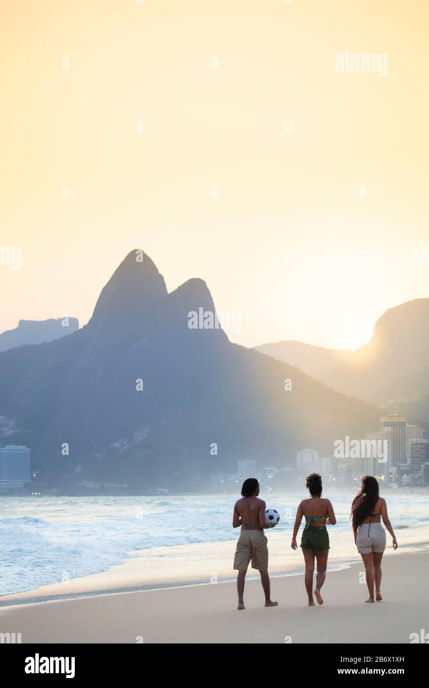 Un gruppo di amici locali che camminano lungo la spiaggia di Ipanema a Rio de Janeiro Foto Stock