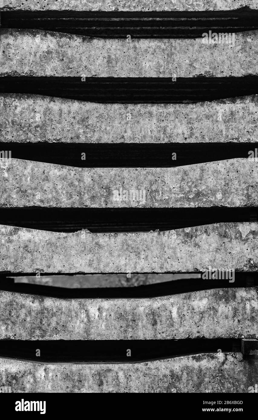 Nuove traversine ferroviarie in calcestruzzo impilate su file pronte per giacere sotto il binario ferroviario come sfondo monocromatico Foto Stock