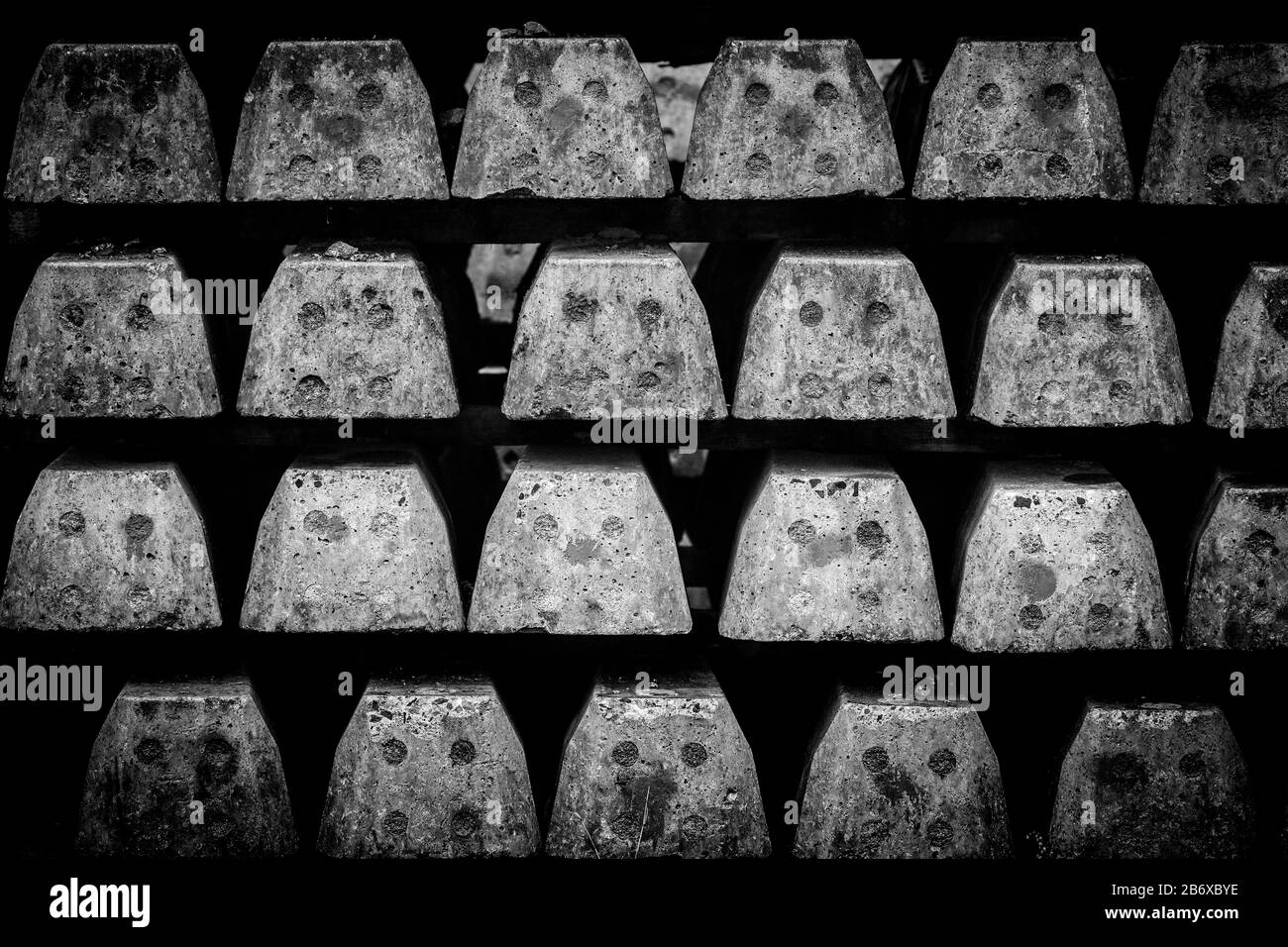 Nuove traversine ferroviarie in calcestruzzo impilate su file pronte per giacere sotto il binario ferroviario come sfondo monocromatico Foto Stock