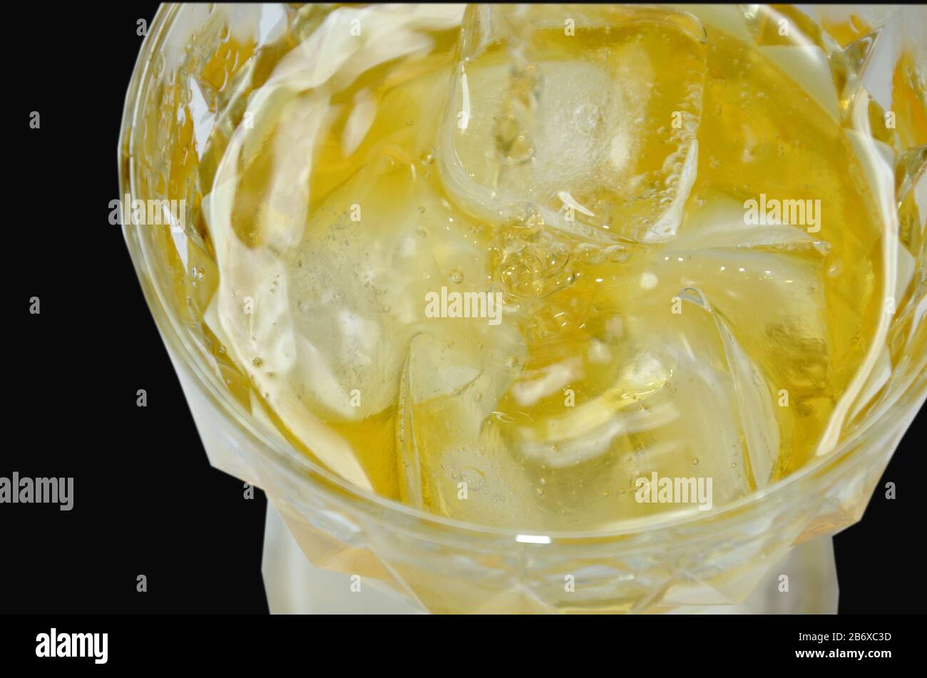 versare il whiskey su ghiaccio su fondo nero Foto Stock