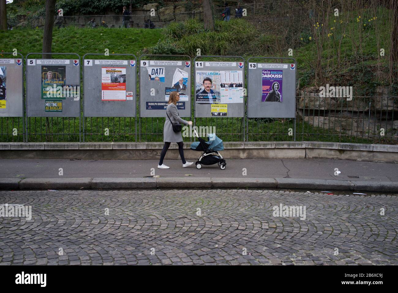 Donna con carrozzina passa accanto a pannelli che mostrano candidati elettorali in esecuzione nelle elezioni comunali francesi, rue Ronsard, Montmartre, 75018 Parigi, Francia, marzo 2020 Foto Stock