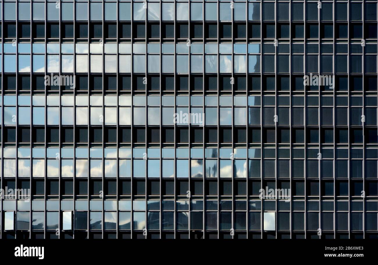 Facciata a parete con tende di vetro di un edificio generico e moderno, con il cielo riflesso sulla sua superficie Foto Stock