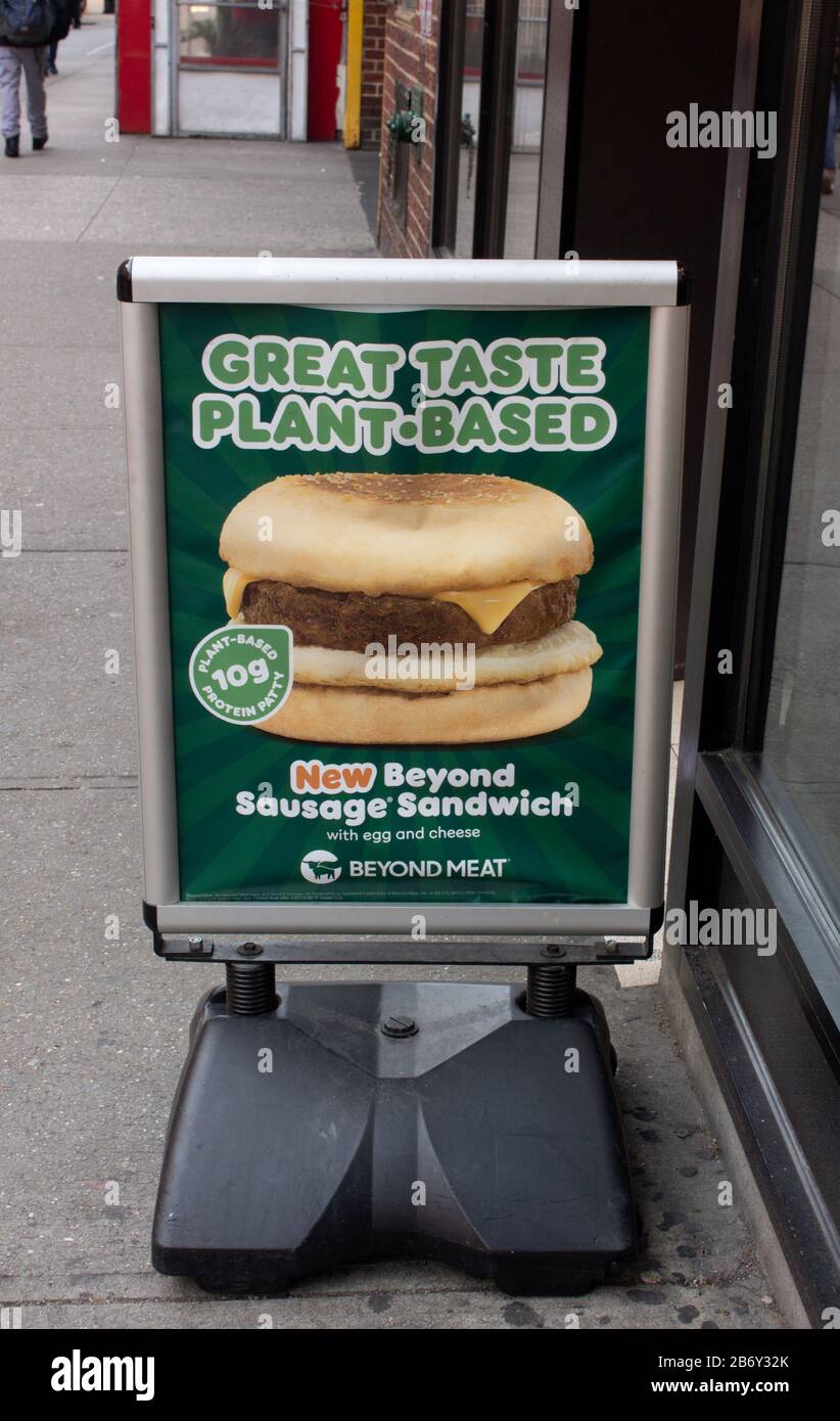 un cartello di fronte a un dunkin ciambelle che pubblicizzano panini con salsiccia senza carne Foto Stock