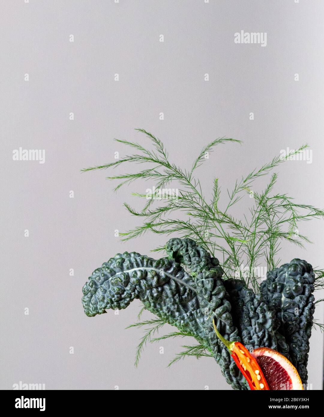 disposizione delle foglie di kale con arancia e peperoncino su fondo bianco con spazio per le copie Foto Stock
