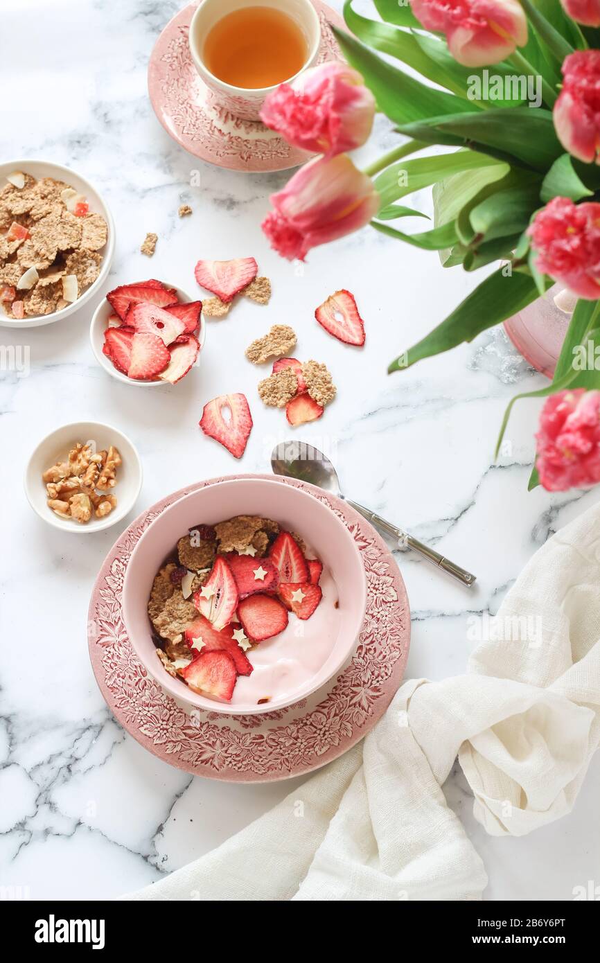 Tavolo luminoso per la colazione con yogurt, muesli e fragole secche Foto Stock