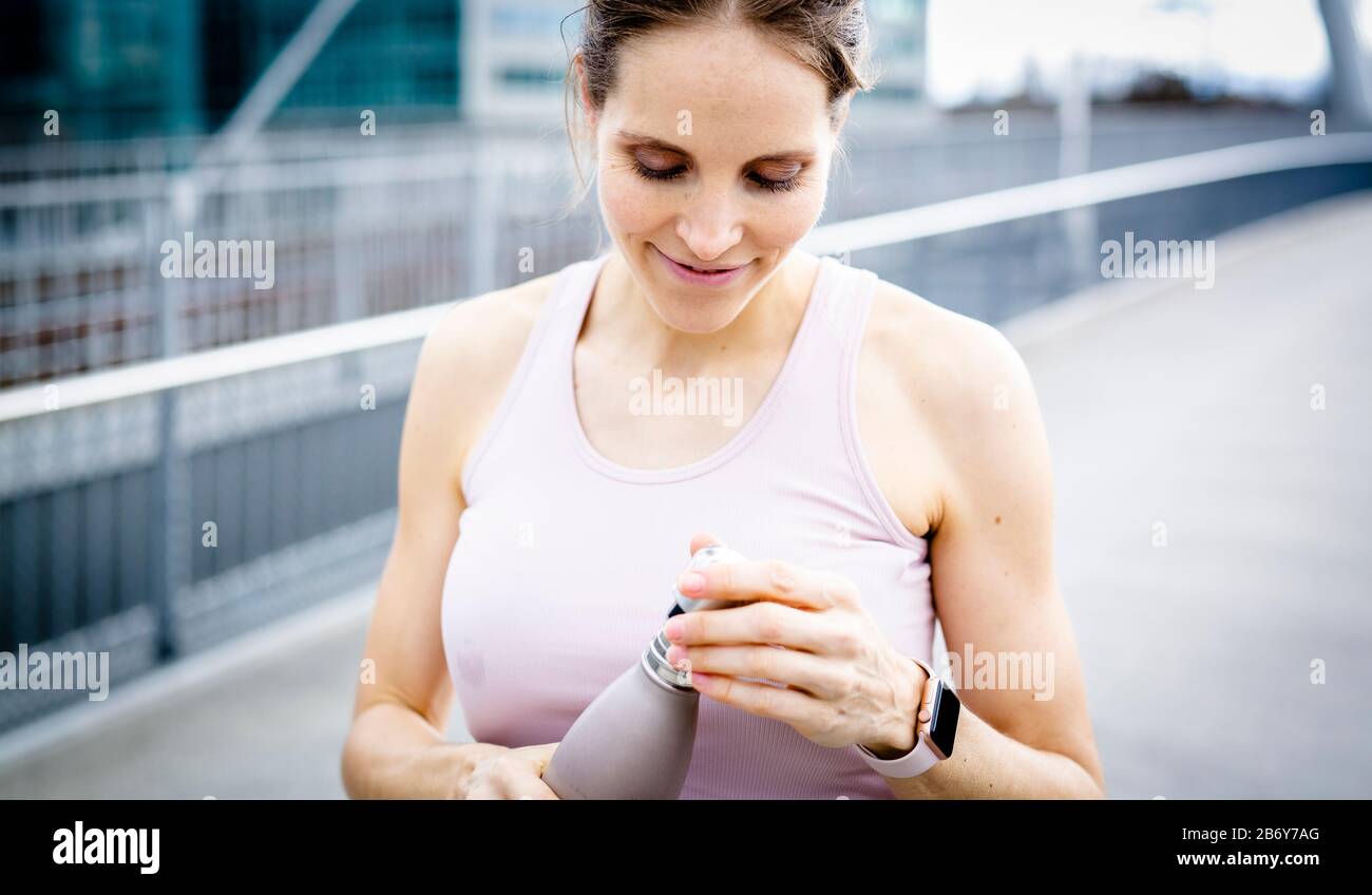 Junge atletische Frau nach dem Joggen mit Wasserflasche in der hand.Young donna atletica dopo jogging con bottiglia d'acqua in mano. Foto Stock