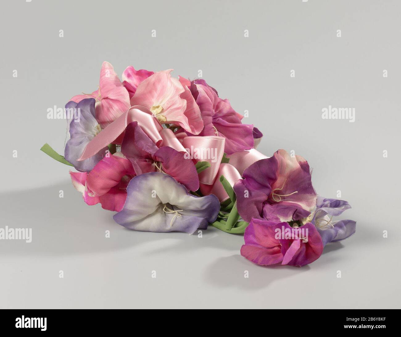 Kapje met wende-bloemen Kapje van bruin tarlatan geheel versierd met roze en paarsblauwe winde van zijde en een roze satijnen strik, achter drie afhangende bloemen Kapje van bruin tarlatan geheel versierd met roze en paarsblauwe vende van zijde en rojen. Achter drie afhangende bloemen. Parijs, ca. 1950. Produttore : modiste: Elsa SchiarelliPlats fabbricante: Parijs Dating: CA. 1948 - ca. 1952 Kenmerken Fisico: Satijn en zijde en tarlatan Materiale: Versione: Satijn versione: Zijde geheel: Tarlatan elastiek tule metaal dimensioni: Geheel: H 15 cm. (afhangende bloem Foto Stock