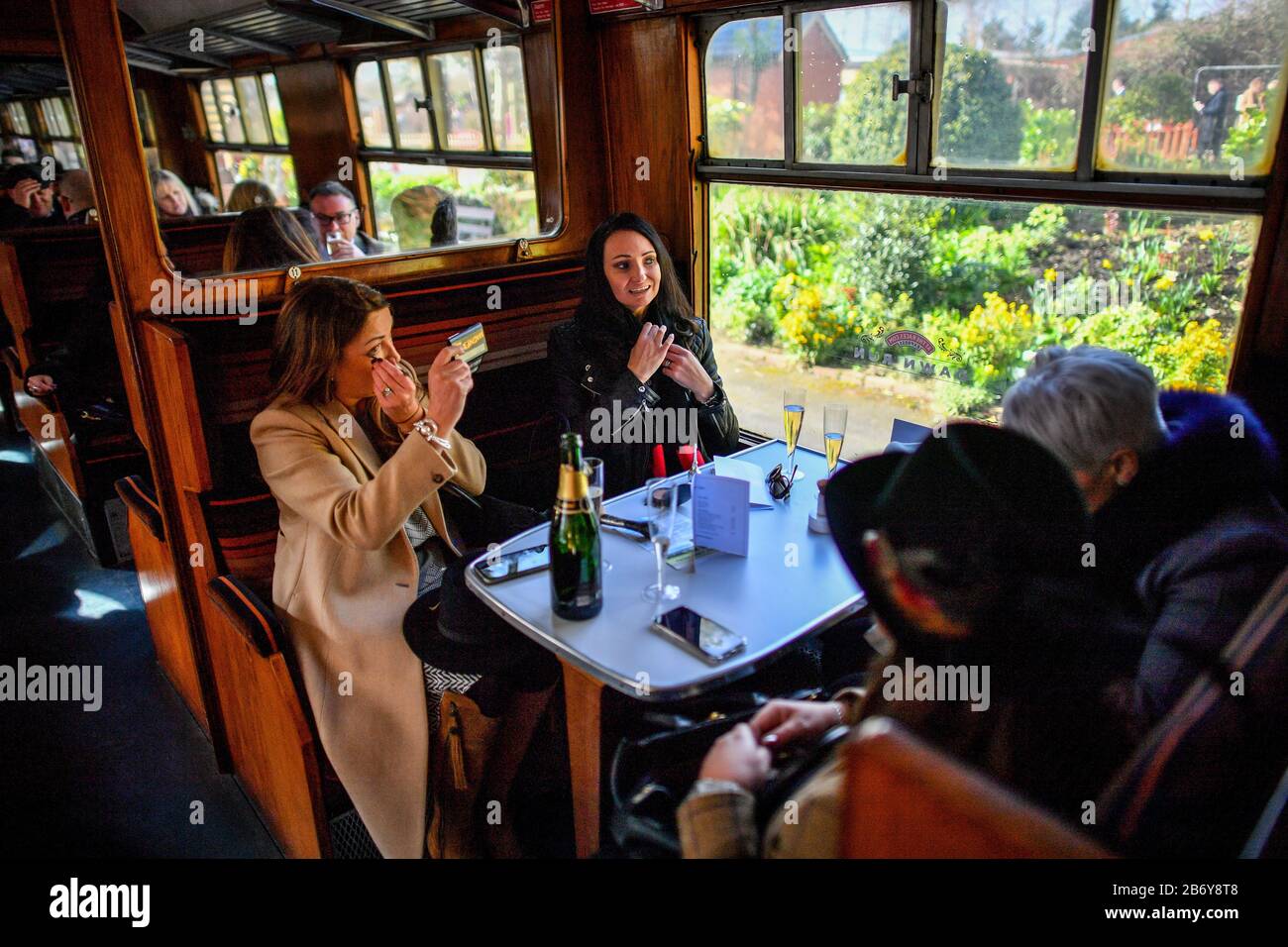 Racegoers controllare il make-up a bordo di una carrozza ferroviaria d'epoca presso la stazione di Toddington, Gloucestershire, dove la gente sta prendendo un treno a vapore per le corse di Cheltenham che sta correndo durante il festival. Foto Stock