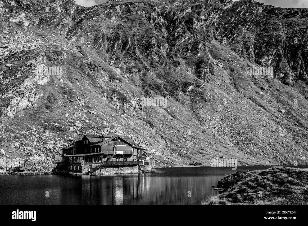Composizione in bianco e nero del lago di montagna con chalet di montagna e montagna sullo sfondo Foto Stock