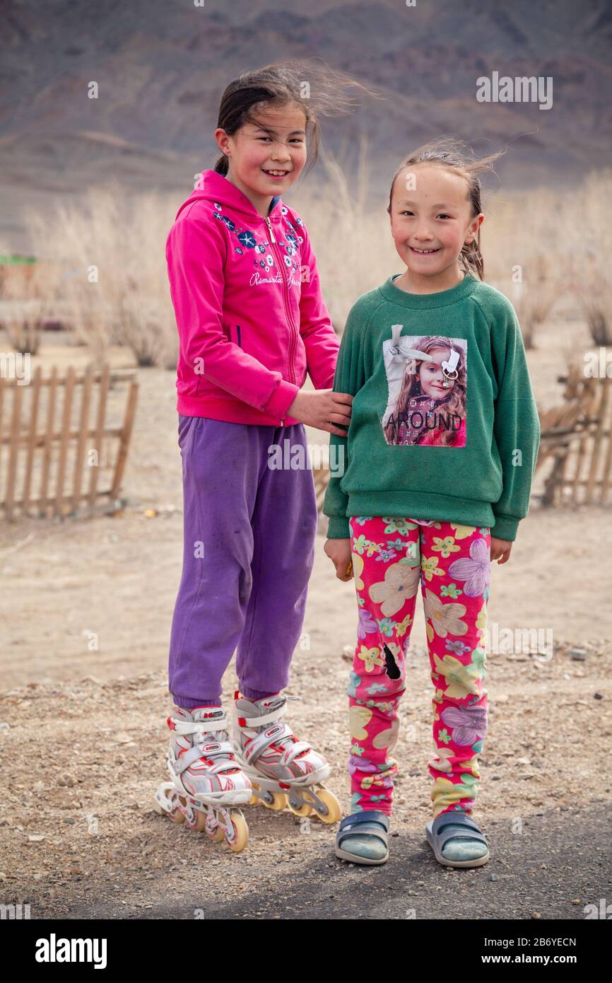 Mongolia Ulgii 2019-05-05 Due ragazze mongolo sorridenti in abiti colorati sullo sfondo di recinto, montagne. Concetto di bambino senza dimora, orfano, chi Foto Stock