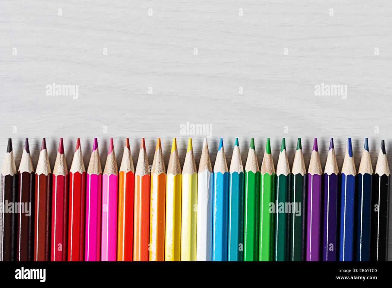 Fila di matite colorate su sfondo di legno bianco vista dall'alto. Concetto  di istruzione. Tavolozza arcobaleno di matite da disegno. Spazio di copia  Foto stock - Alamy