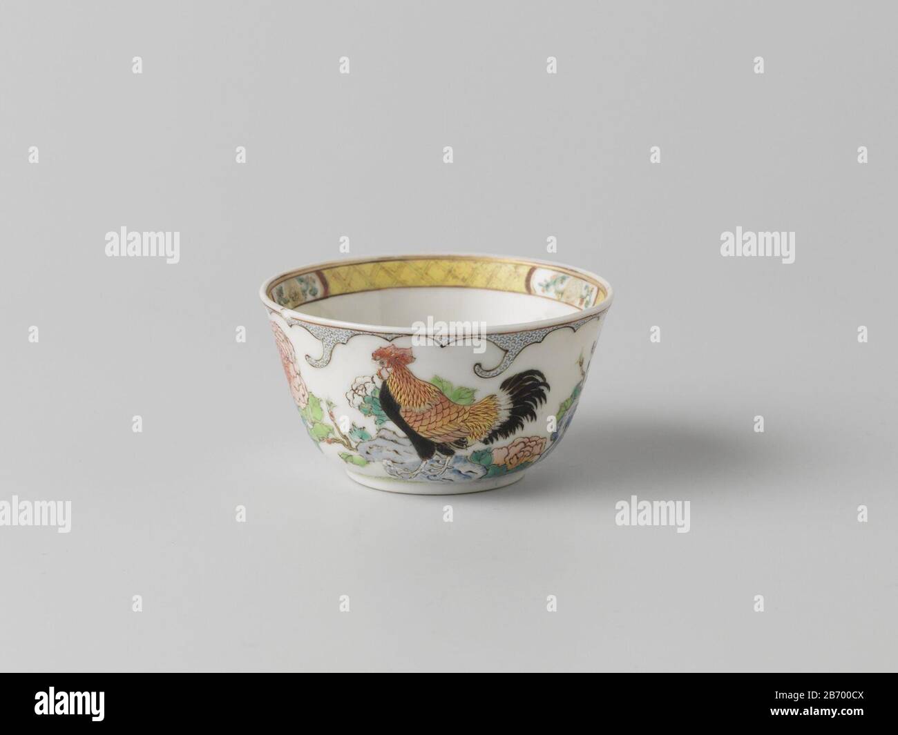 Klokvormige kop met een haan op een errots met bloeiende planten Klokvormige kop van porselein, beschilderd op het glazuur in blauw, rood, roze, groen, geel, zwart en goud. Een bladvormig cartouche met een haan op een errots bij bloeiende pienplanten, om het blad servetwerk afgebeeld; naast de haan een inscripttizend 'Gong ming fu gui jiachen huazhao yie yu Zhujiang jingshe', 'Eer en rijkdom. Geschreven op de dag van de bloemen in het jaar jiachen [1724] in een mooi huis aan de Zhujiang rivier', en een zegelmerk 'Baishi', 'witte steen'; op de rand een band servetwerk afgewisseld met een bloemr Foto Stock