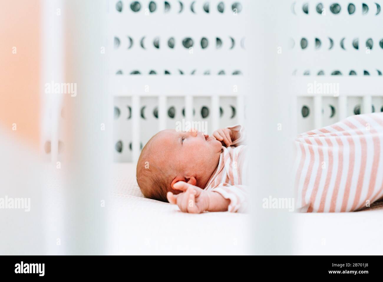 Vista laterale di una ragazza neonato che si posa nel suo moderno presepe Foto Stock