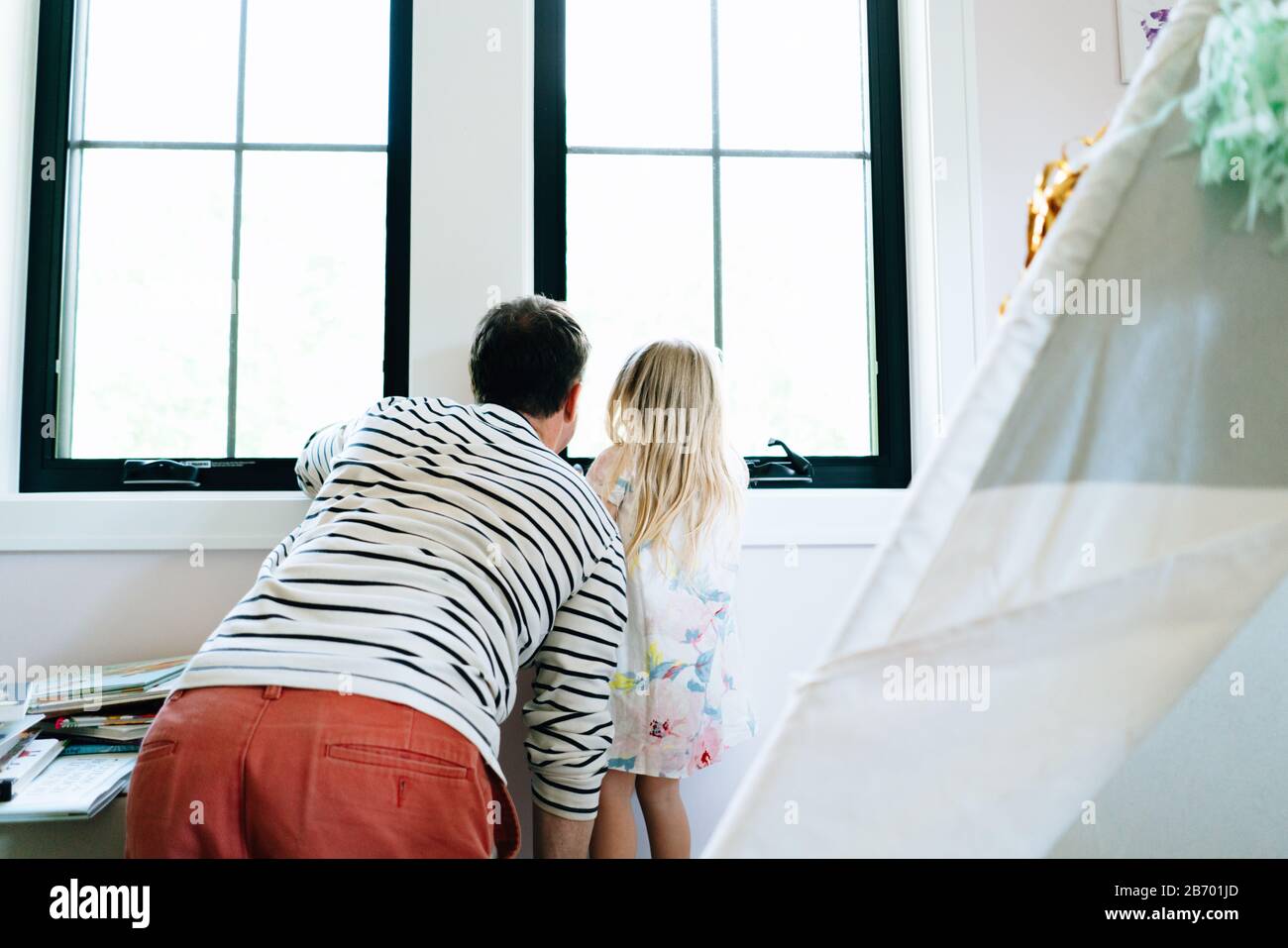 Vista da dietro di un padre e una figlia che si affaccia su una finestra Foto Stock