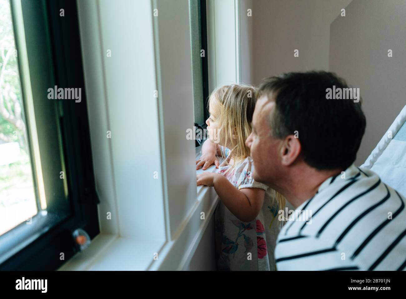 Vista laterale di un padre e di una figlia che guardano una finestra Foto Stock