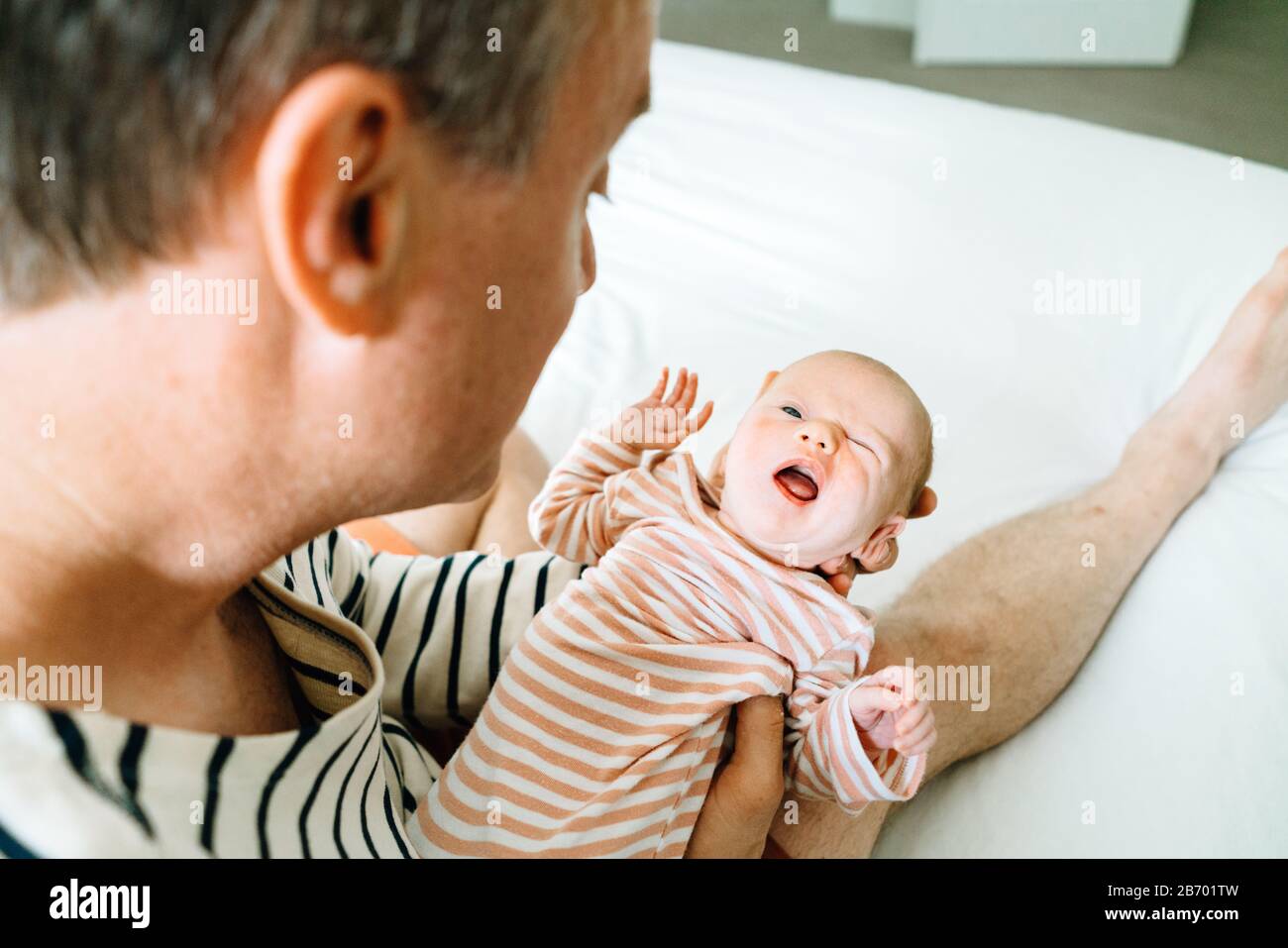 Ritratto di primo piano di un neonato che fa un viso divertente mentre è tenuto Foto Stock