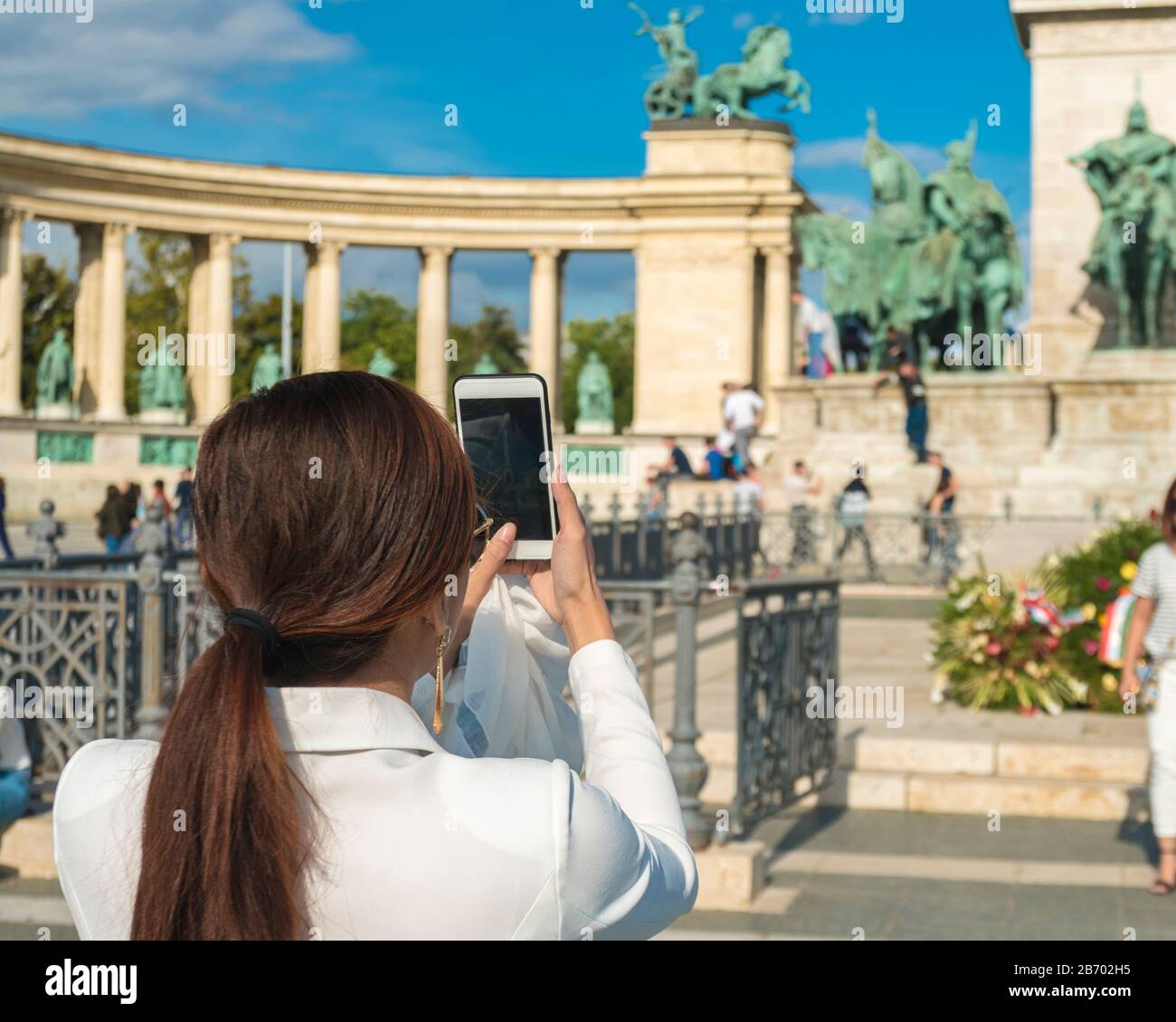 Turista asiatico scattare foto con il telefono dal monumento del Millennio Foto Stock