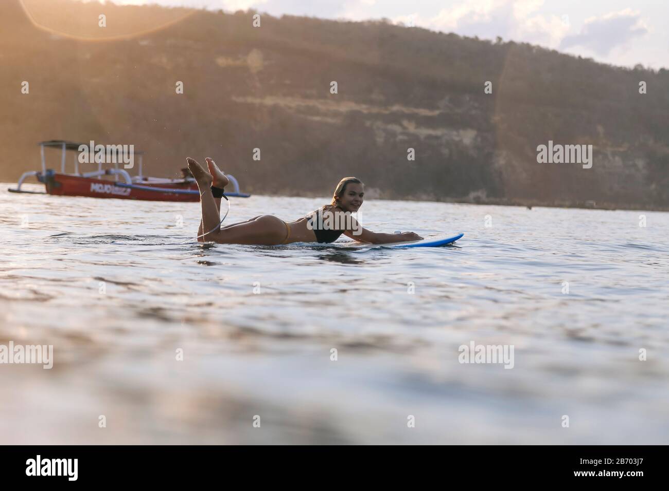Surfista femminile nell'oceano al tramonto Foto Stock