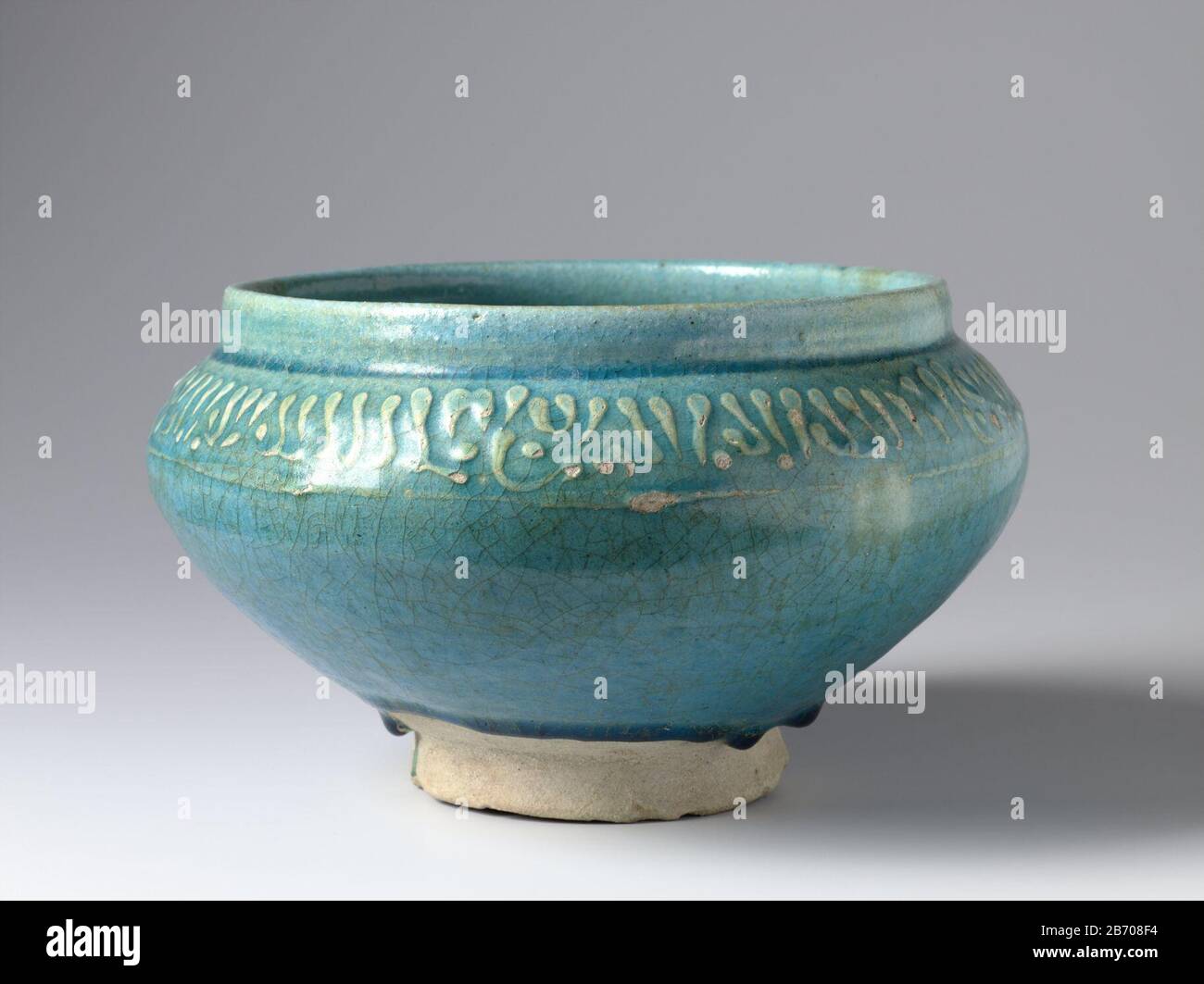 Kom met pseudo-schrift op de schouder Kom van kwarts-fritgoed gedecoreerd met pseudo-schrift in reliëf en bedekt met een trasparente turchese alkalgalazuur. Produttore : pottenbakker: AnoniemPlaats fabbricante: Iran Dating: CA. 1100 - ca. 1299School / stijl: Seltsjoeken / Ilkhanieden Physical kenmerken: Aardewerk (kwarts-fritgoed) Met glazuur Materiale: Aardewerk kwarts-fritgoed glazuur Techniek: Vormen / bakken / reliëf / glazuren dimensioni: H 13,6 cm. Rand: D 20,3 cm. Buik: D 23,4 cm. D et D 10,3 cm. Foto Stock