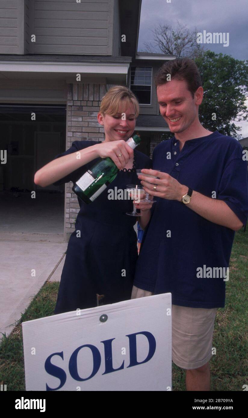 Austin, Texas: La coppia si erge orgogliosa di fronte alla loro prima casa recentemente acquistata mentre si prepara un brindisi con champagne. SIGNOR ©Bob Daemmrich Foto Stock