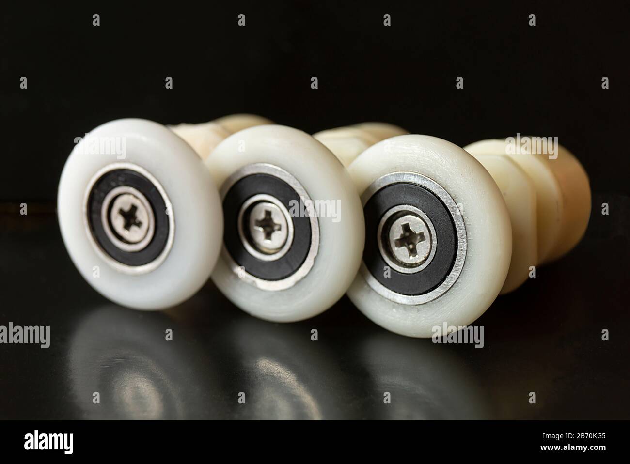 Rullo bianco con vite su sfondo nero.primo piano ruota in plastica Foto Stock