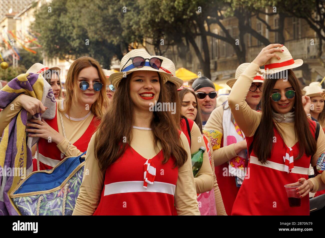 Rijeka, Croazia, 23 febbraio 2020. Allegro, sorridente, felice ragazze e giovane donna con cappelli e bicchieri a piedi nella sfilata di carnevale di strada Foto Stock