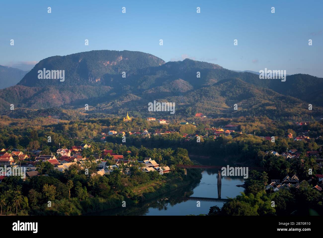 Vista elevata della città di Luang Prabang, Laos, attraversata dal fiume Nam Kham e circondata da fitta foresta pluviale, nel pomeriggio. Foto Stock