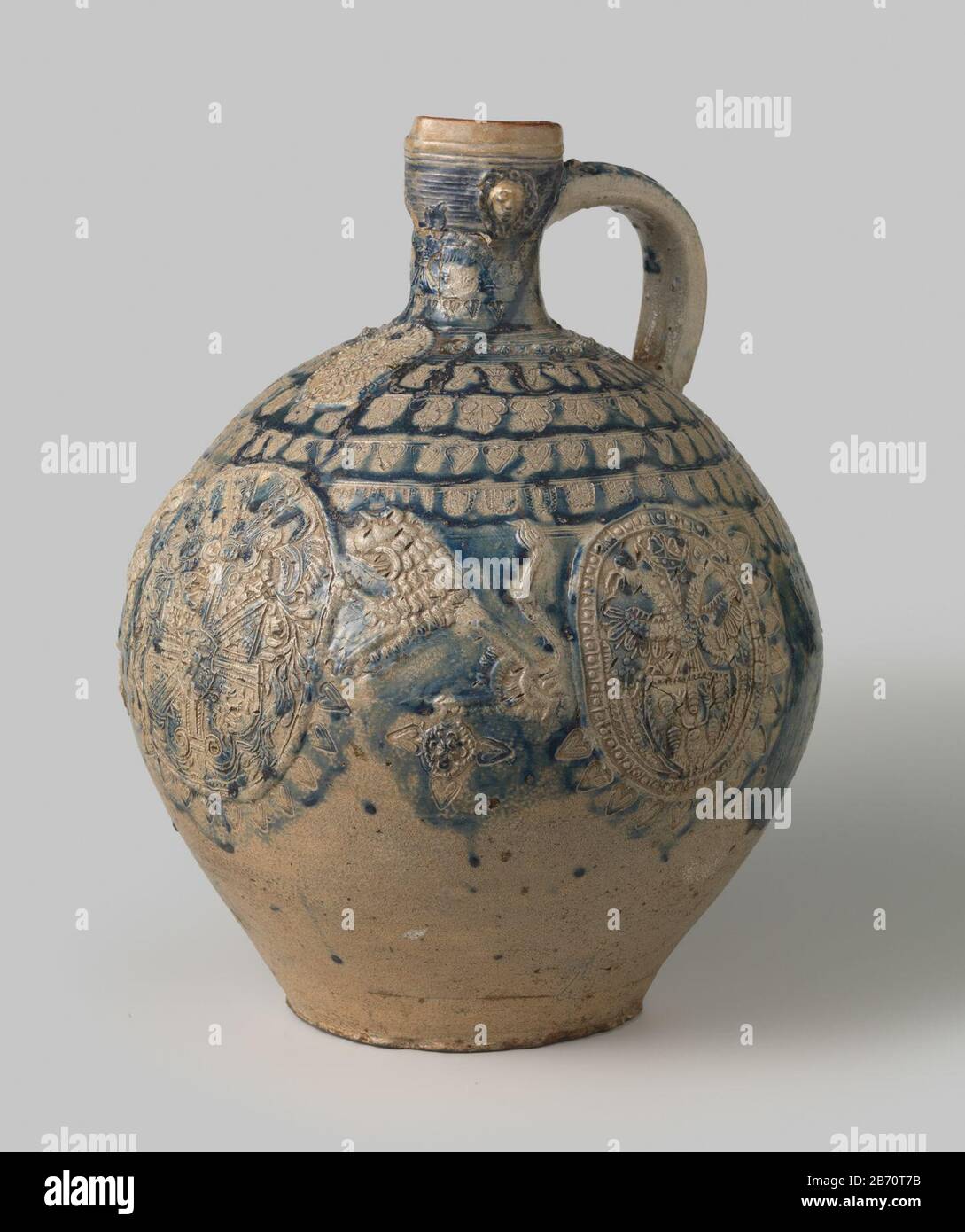 Kruik met wapens, leeuwen en decoratieve banden Kruik van steengoed op standvlak met een bolvormig lichaam en smalle nek. Het C-vormige o è vestigd aan de nek en de schouder. Profielen op de nek. Gedeeltelijk bedekt met kobaltblauw. Op de buik drie gedrukte en opgelegde medaillons a reliëf met wapens, Foto Stock