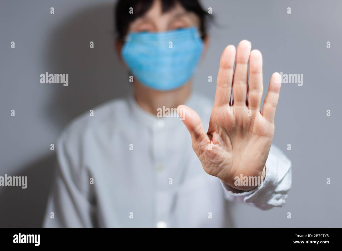 Arrestare la quarantena del coronavirus e il concetto di inquinamento atmosferico pm2.5. Donna anziana malata che indossa maschera respiratore per proteggere con braccio allungato. Wuhan, Cina ep Foto Stock