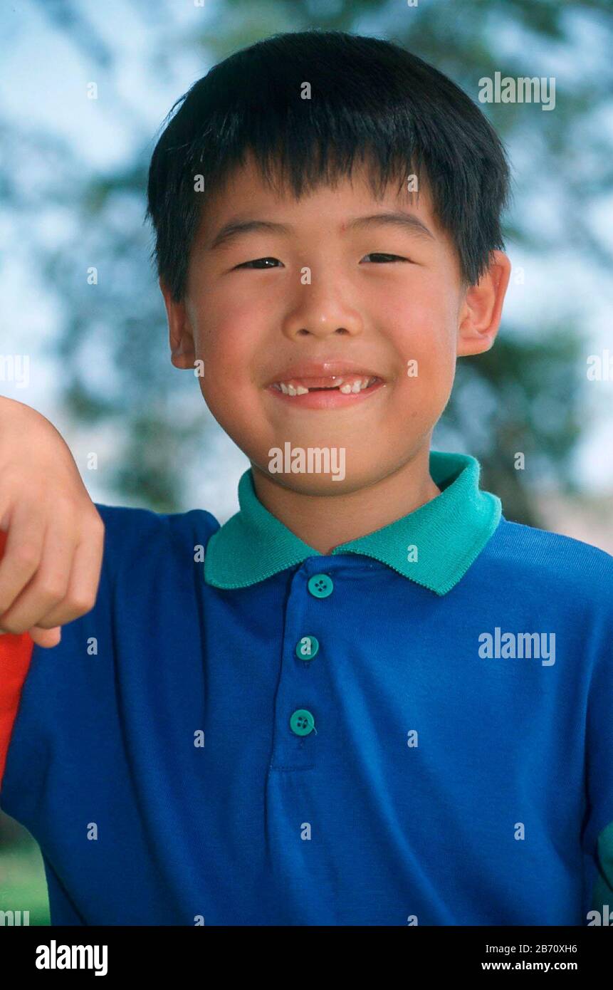 Austin, Texas USA: Il giovane ragazzo asiatico-americano che manca i suoi due denti anteriori si pone per il ritratto all'aperto. SIGNOR ©Bob Daemmrich Foto Stock