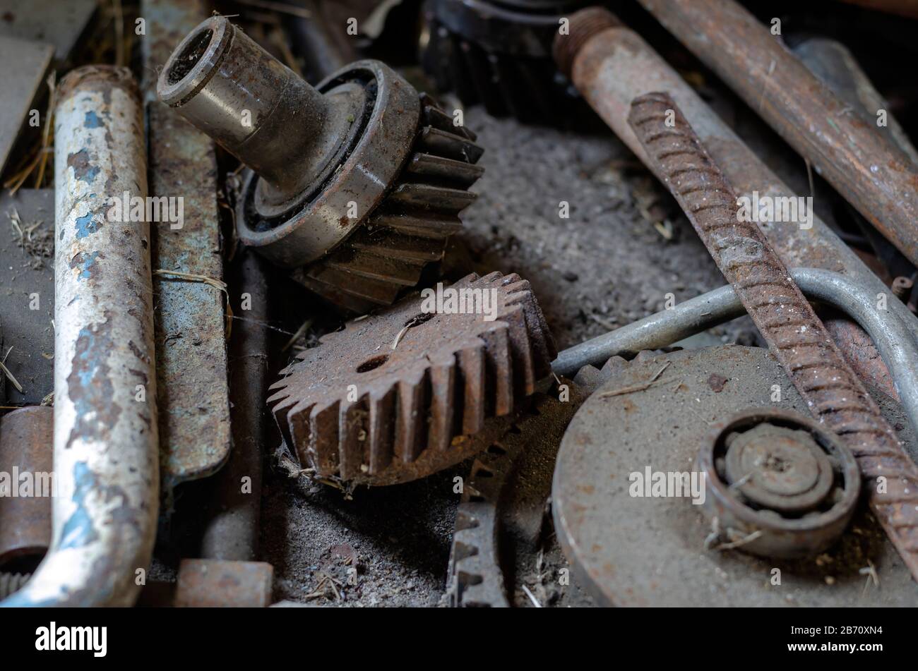 Il metallo arrugginito e gli ingranaggi giacciono caoticamente. Primo piano  di vecchi ingranaggi, cuscinetti e tubi. Vecchio banco da lavoro ricoperto  di polvere e ciottoli. Contesto industriale. Sel Foto stock - Alamy