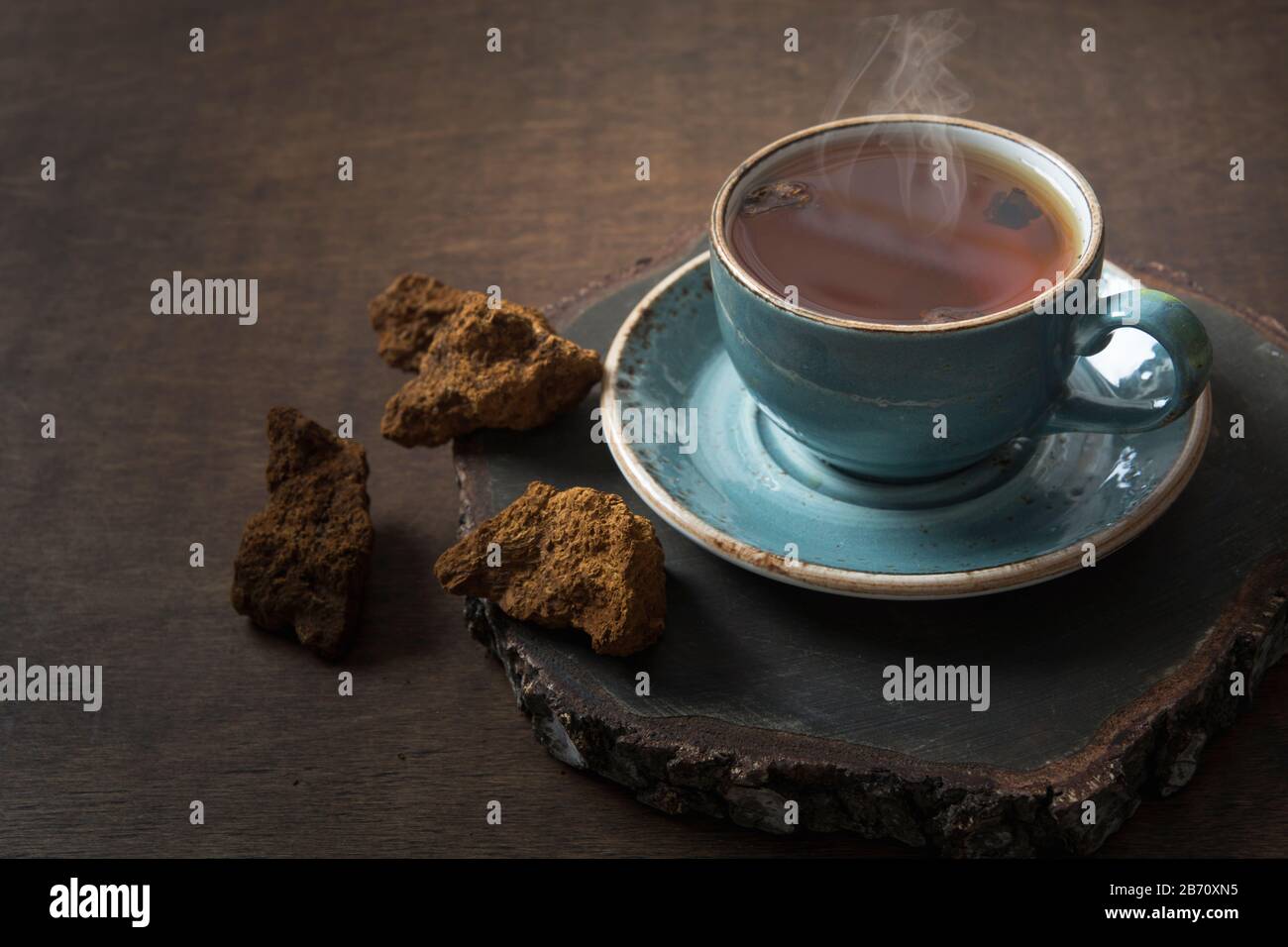 Funghi Chaga biologico caffè caldo in tazza di vetro. Trendy sano bere mangiare su sfondo di legno scuro. Primo piano. Foto Stock