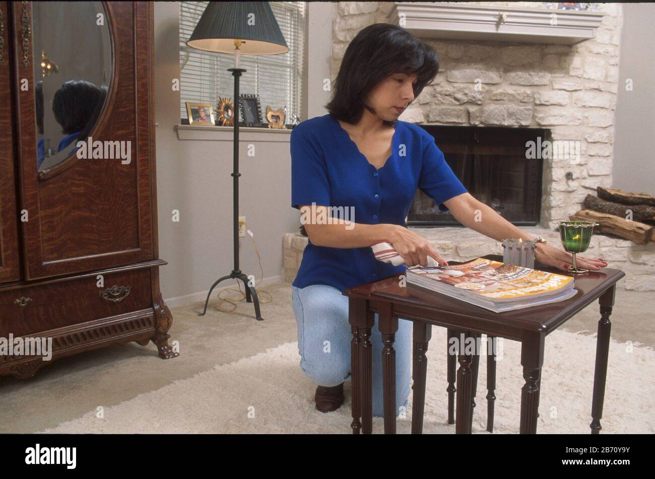 Donna che mostra disturbo ossessivo-compulsivo raddrizzando il tavolino da caffè più e più nel suo salotto. ©Bob Daemmrich Foto Stock