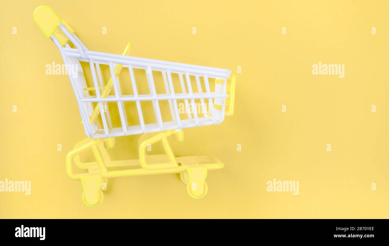 Shopping piccolo trolley su sfondo giallo, Copia spazio. Vendita o acquisto di concetto di consumatore Foto Stock