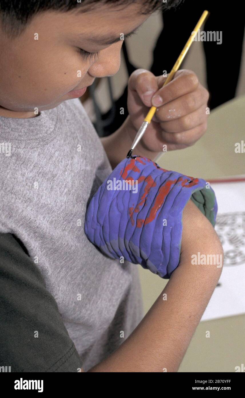 Austin Texas USA: Formazione bilingue: Studente in quinta classe d'arte pittura indiana 'pelle animale' disegni su ceramica. ©Bob Daemmrich Foto Stock