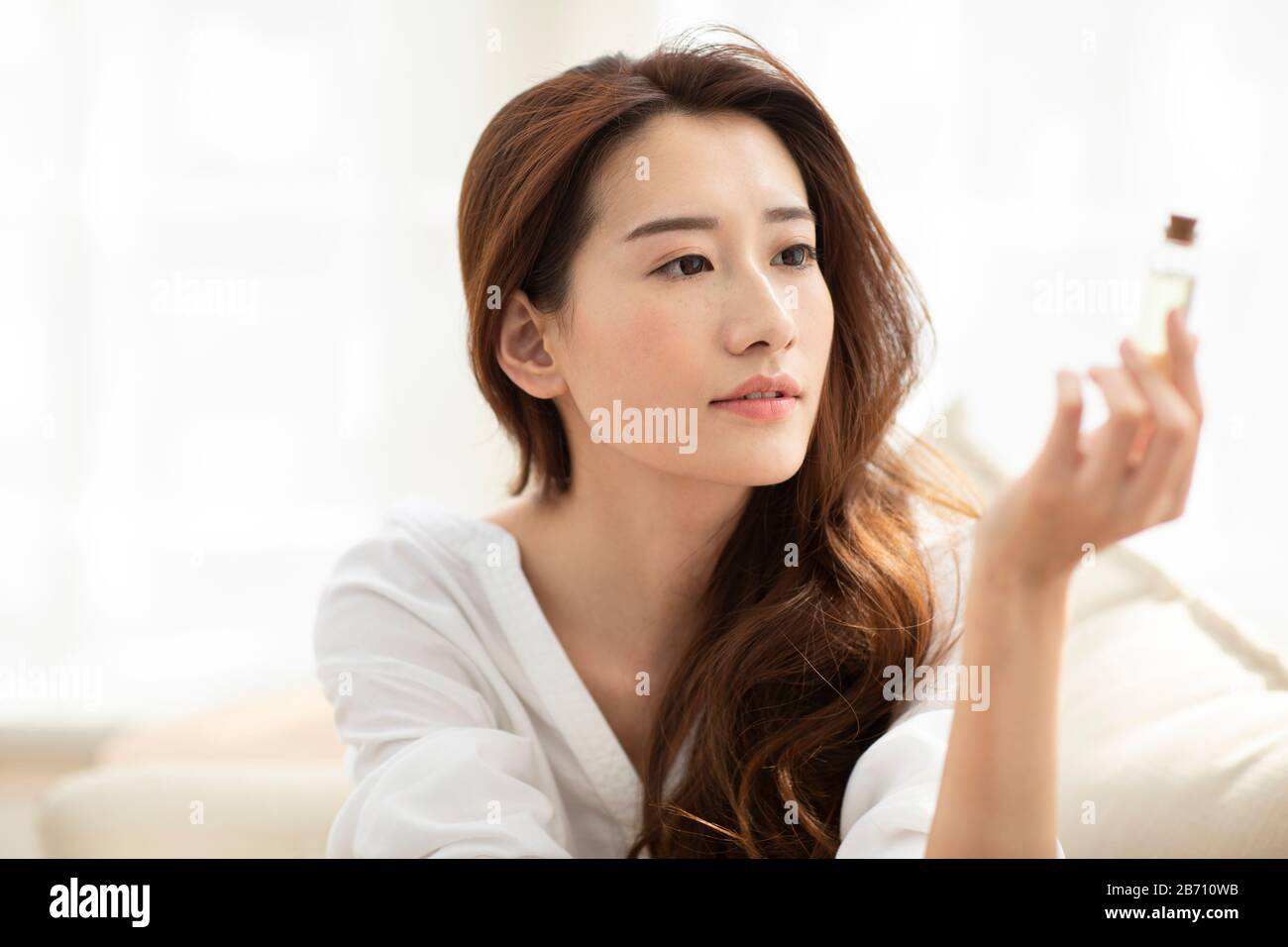 Giovane donna cinese che applica l'olio essenziale sui capelli Foto Stock