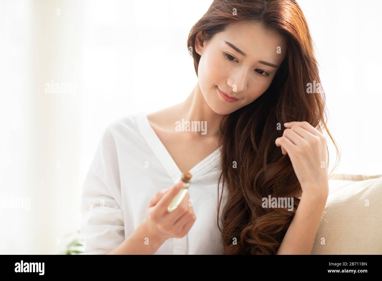 Giovane donna cinese che applica l'olio essenziale sui capelli Foto Stock