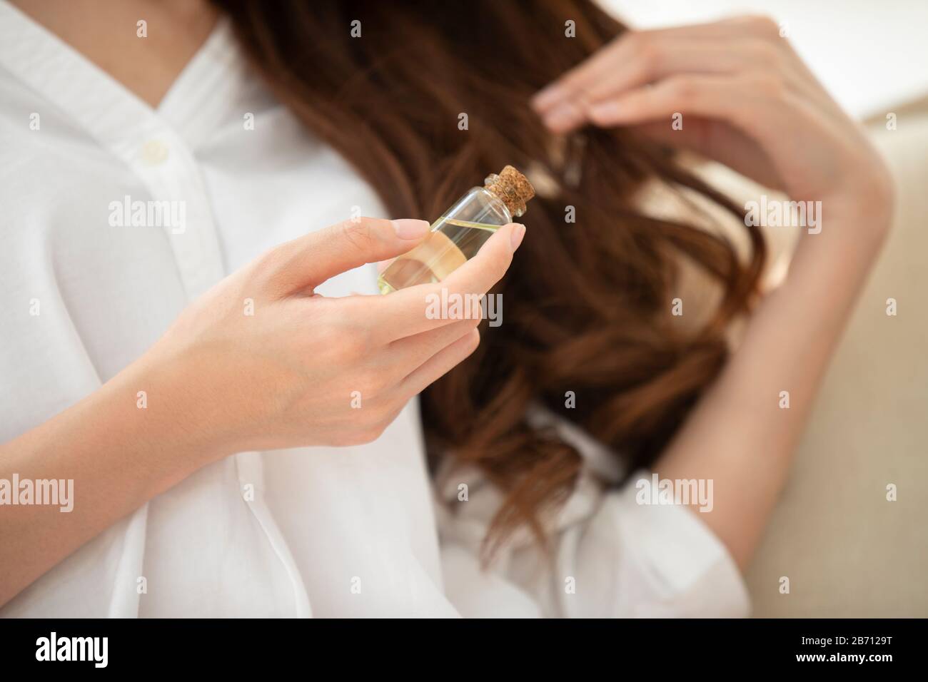 Giovane donna cinese che applica l'olio essenziale sui capelli Foto Stock