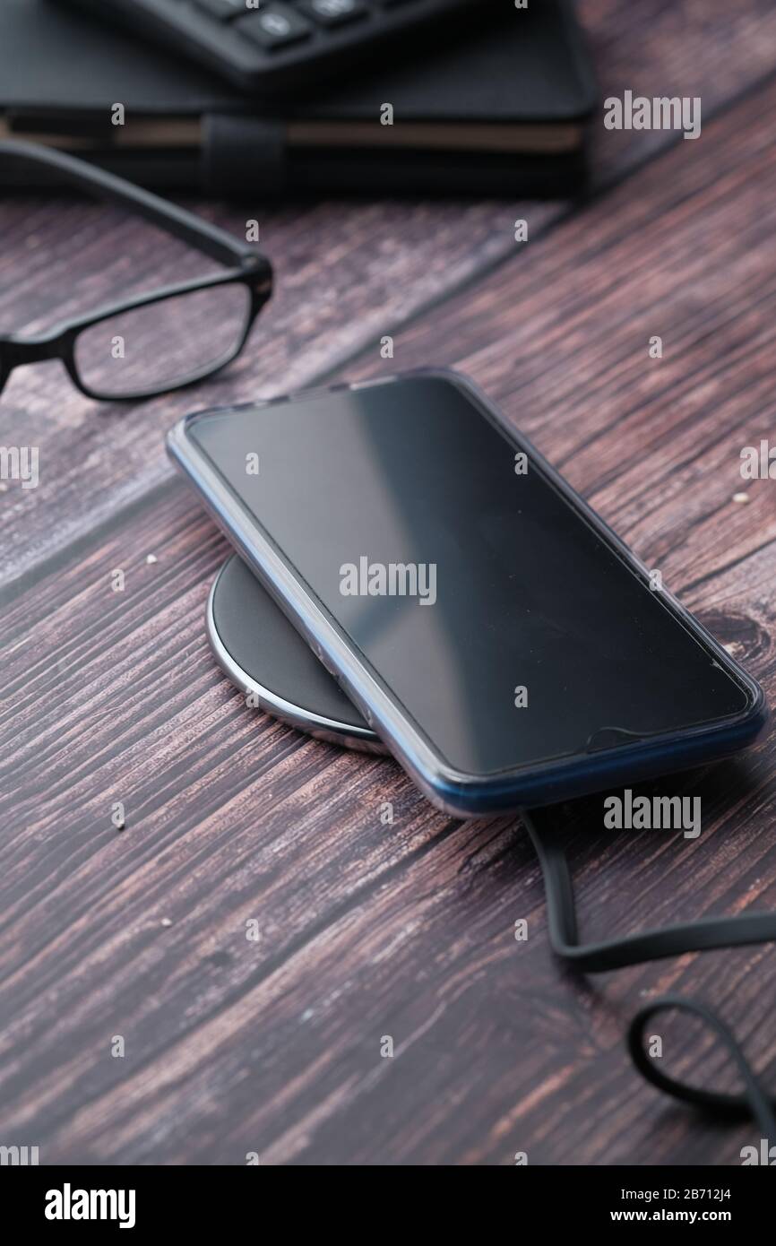 Primo piano della ricarica dello smartphone sul tavolo Foto Stock