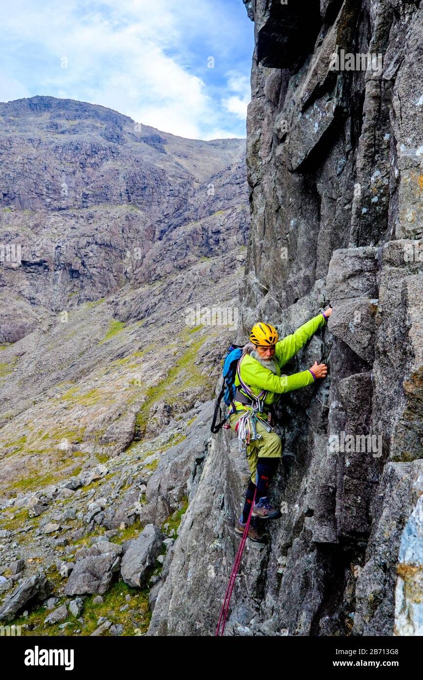 Scalatore di roccia che arrampica un percorso nelle montagne di Cuillin di Skye, Scozia Foto Stock