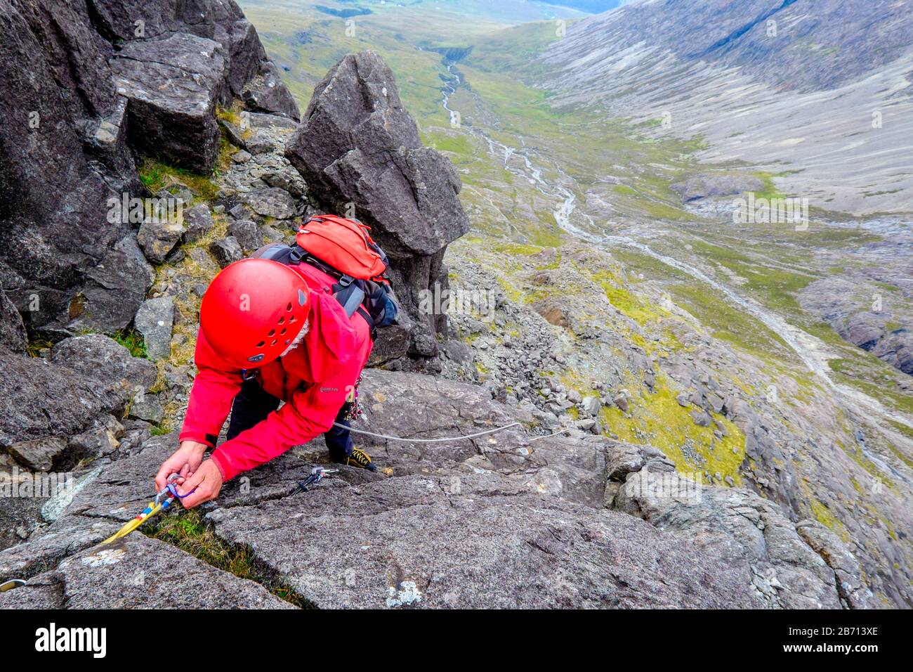 Un arrampicatore di roccia che istituisce un belay nelle montagne di Cuillin di Skye, Scozia Foto Stock