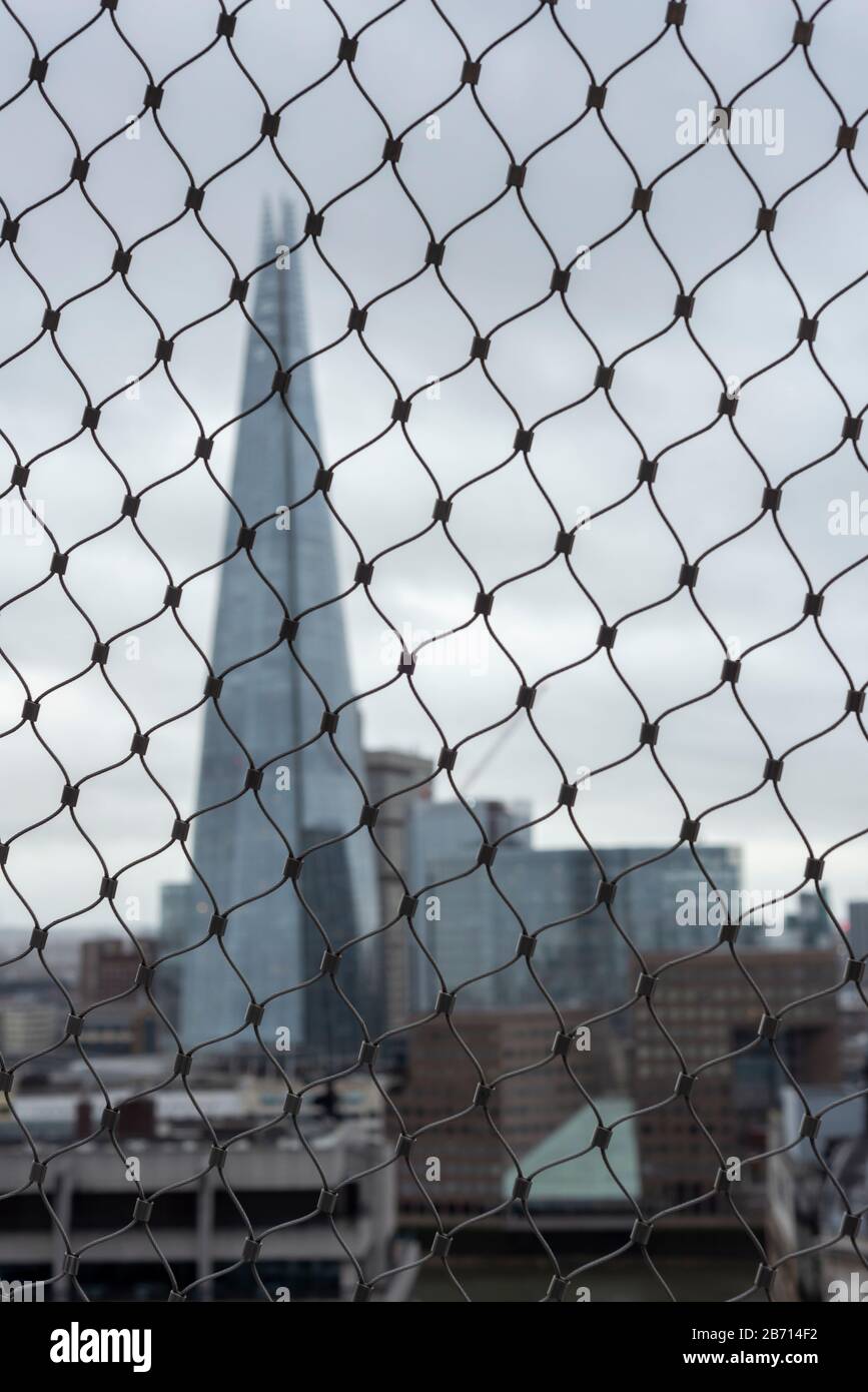 Insolita vista ostruita dell'edificio Shard attraverso la recinzione a rete metallica dalla cima del Monumento, Londra, Regno Unito Foto Stock