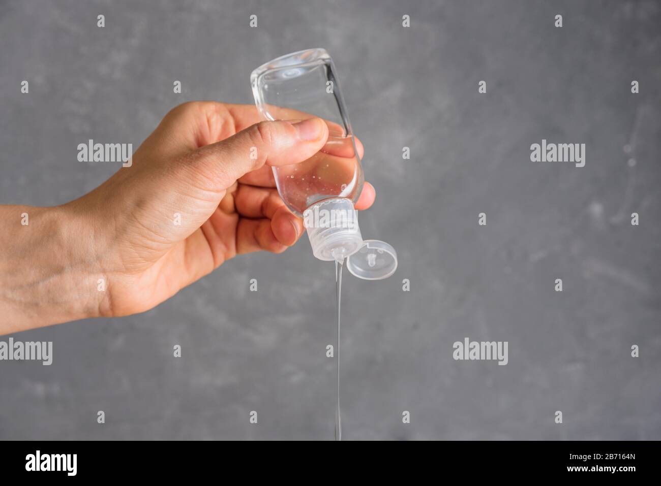 Utilizzo di igienizzatore per mani su sfondo grigio. Concetto di igiene personale Foto Stock