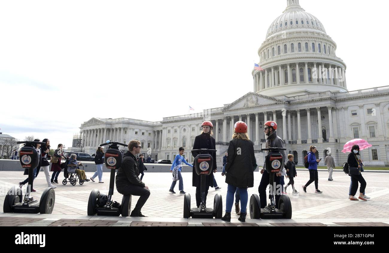 Washington, Stati Uniti. 12th Mar, 2020. I turisti su Electric Segways si fermino sulla Capitol plaza degli Stati Uniti mentre altri camminano intorno, uno che indossa un facemask protettivo, giovedì 12 marzo 2020, a Washington, DC. Il Campidoglio si chiuderà ai visitatori alla fine della giornata e non riaprirà fino al 1° aprile, mentre il governo si muove per combattere il Coronavirus. Foto di Mike Theiler/UPI Credit: UPI/Alamy Live News Foto Stock