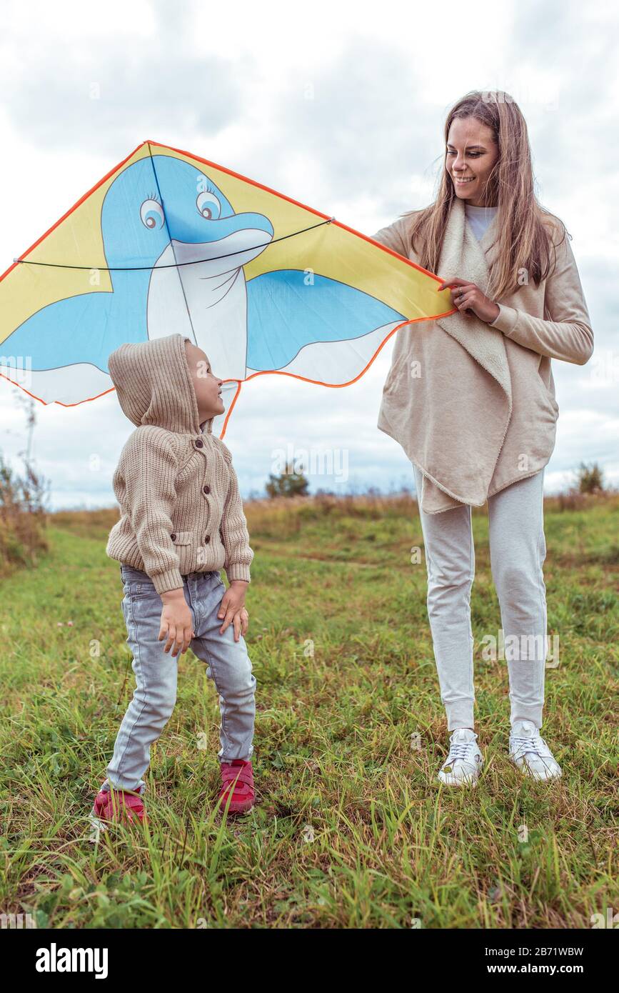 Felice famiglia mamma donna e bambino figlio volare kite, estate autunno giorno in campo. Emozioni di felicità, divertimento, gioie di risate e sorriso. Foto Stock