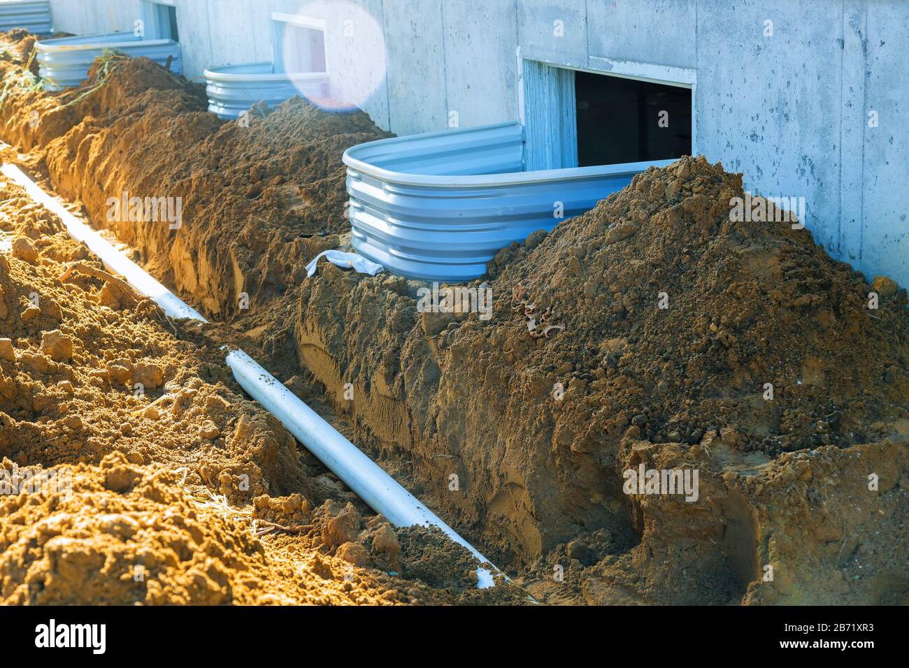 Tubazioni in plastica e una grondaia contro e intorno al tubo di scarico nella casa di terra Foto Stock