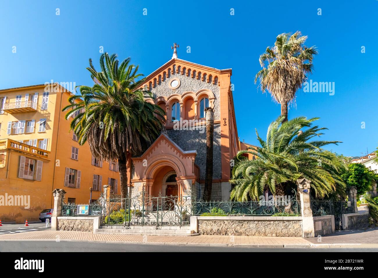 La pittoresca chiesa protestante riformata di Francia circondata da palme nella città mediterranea di Menton, Francia. Foto Stock