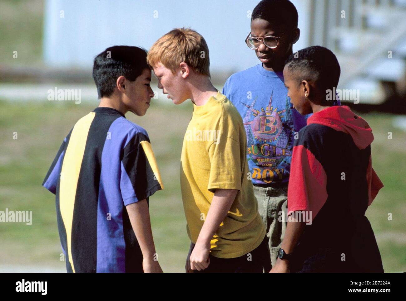 Austin Texas USA: Gli amici preoccupati guardano su come un ragazzo aggressivo sostiene con il compagno di classe sul parco giochi junior delle scuole superiori. ©Bob Daemmrich Foto Stock