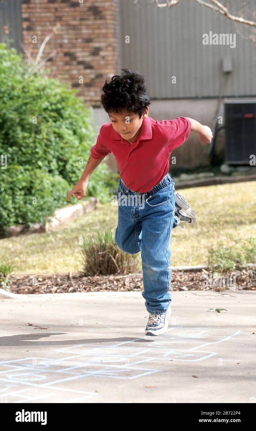 Austin Texas USA, 2001: Ragazzo di sette anni, nativo del Guatemala, che gioca hopscotch nel vialetto della casa della sua famiglia. SIGNOR ©Bob Daemmrich Foto Stock