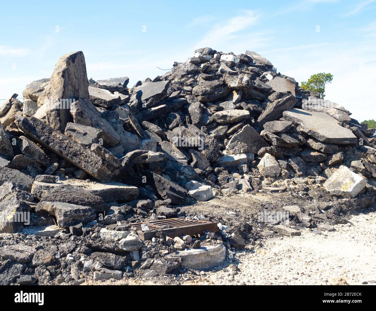 Montagna di asfalto, fondo stradale in cemento e detriti di parcheggio nel cantiere di demolizione stradale, copertura griglia in metallo per scarico fognario, scarico fognario in calcestruzzo Foto Stock